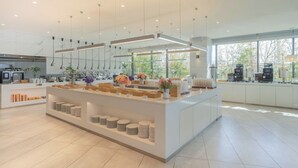 Una cocina moderna con una isla central, iluminación colgante y ventanas amplias.