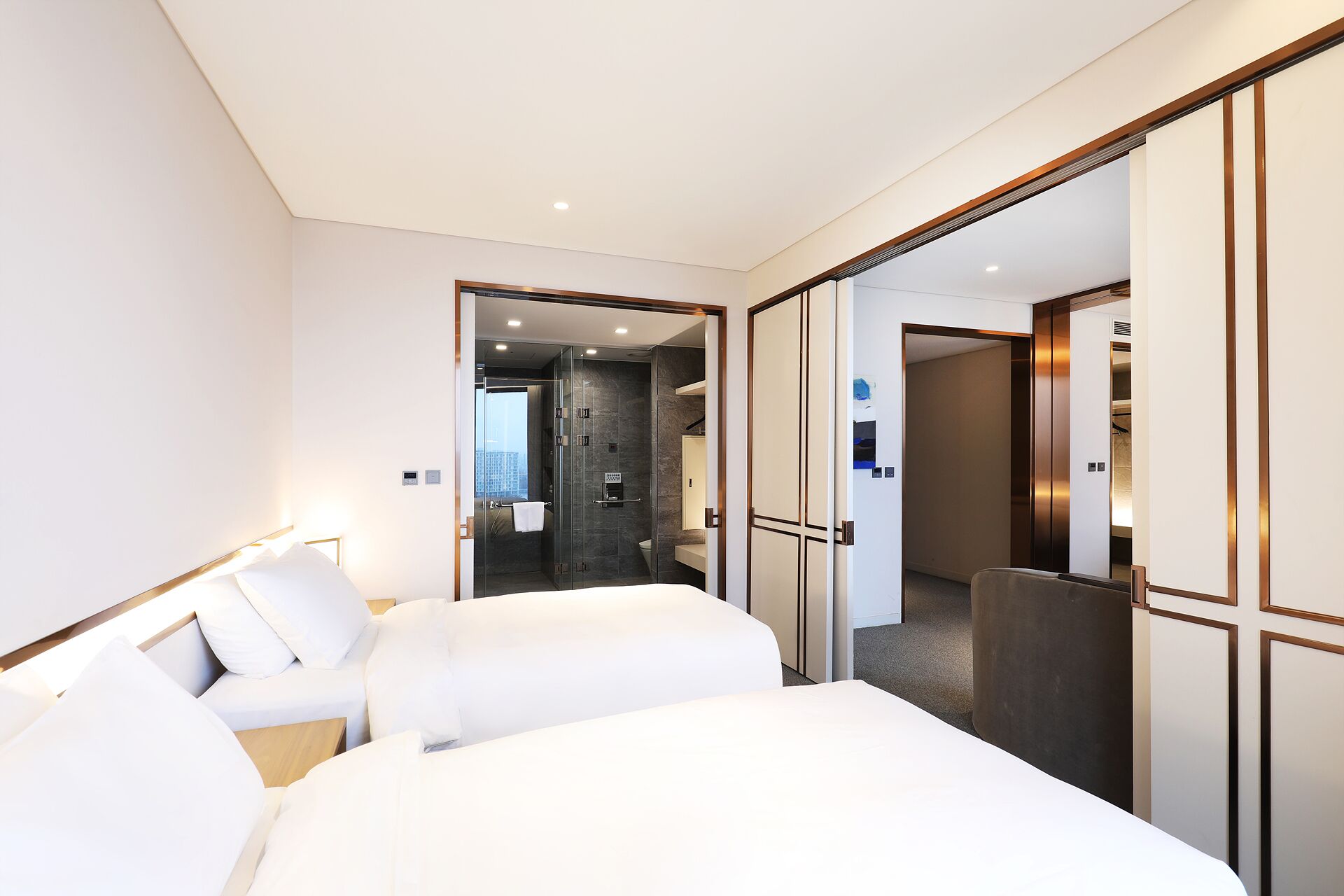 A hotel room with a large bed, a bedside table, a mirror, and a view of the bathroom and hallway.