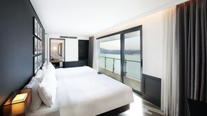 Habitación de hotel moderna con una cama grande, un baño con espejo y un balcón con vistas a la ciudad.