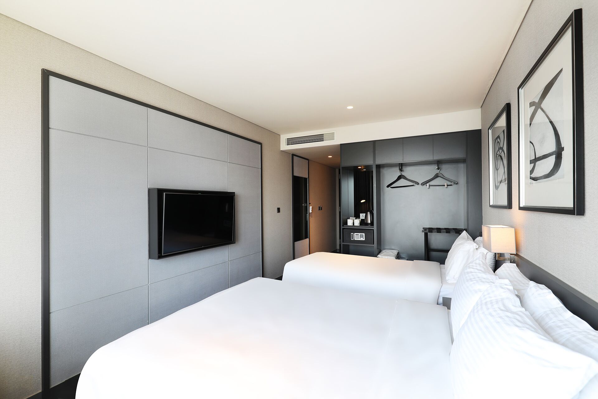 Une chambre d’hôtel avec un grand lit, un téléviseur à écran plat fixé au mur, une armoire et un miroir.