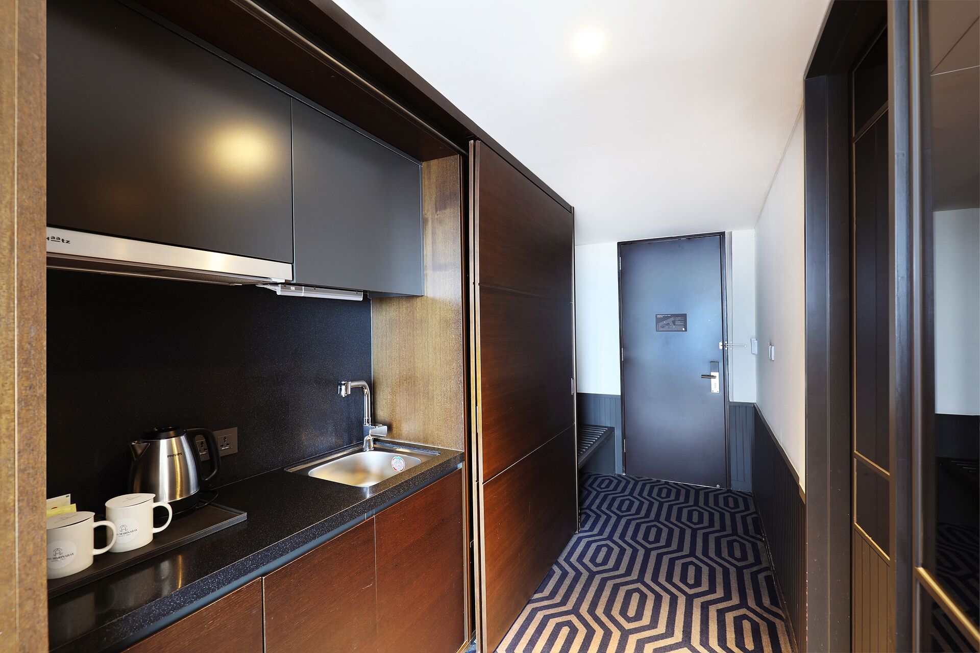 A compact kitchen with dark cabinetry, a stainless steel sink, and a coffee maker.
