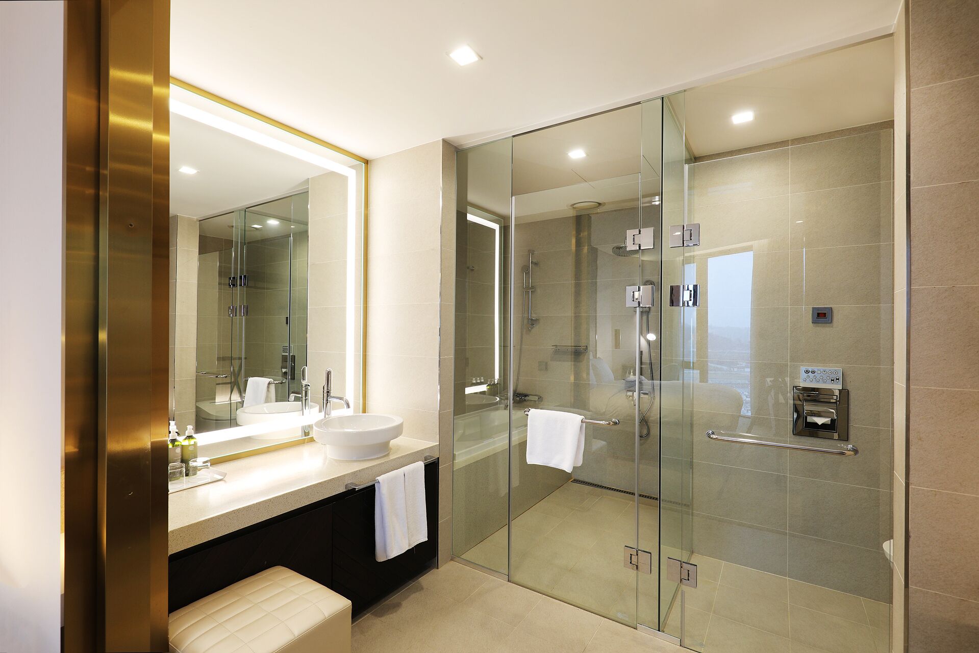 Een moderne badkamer met een douche in een glazen cabine, een grote spiegel en een wastafelmeubel met een wastafel en handdoekhouder.