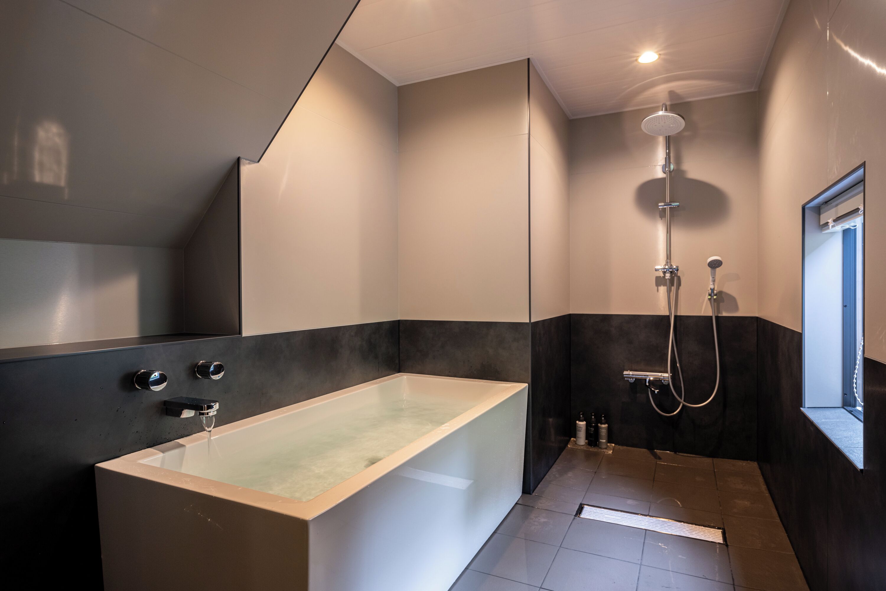 Een moderne badkamer met een vrijstaand bad, een douche en een raam.