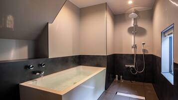 Een moderne badkamer met een vrijstaand bad, een douche en een raam.