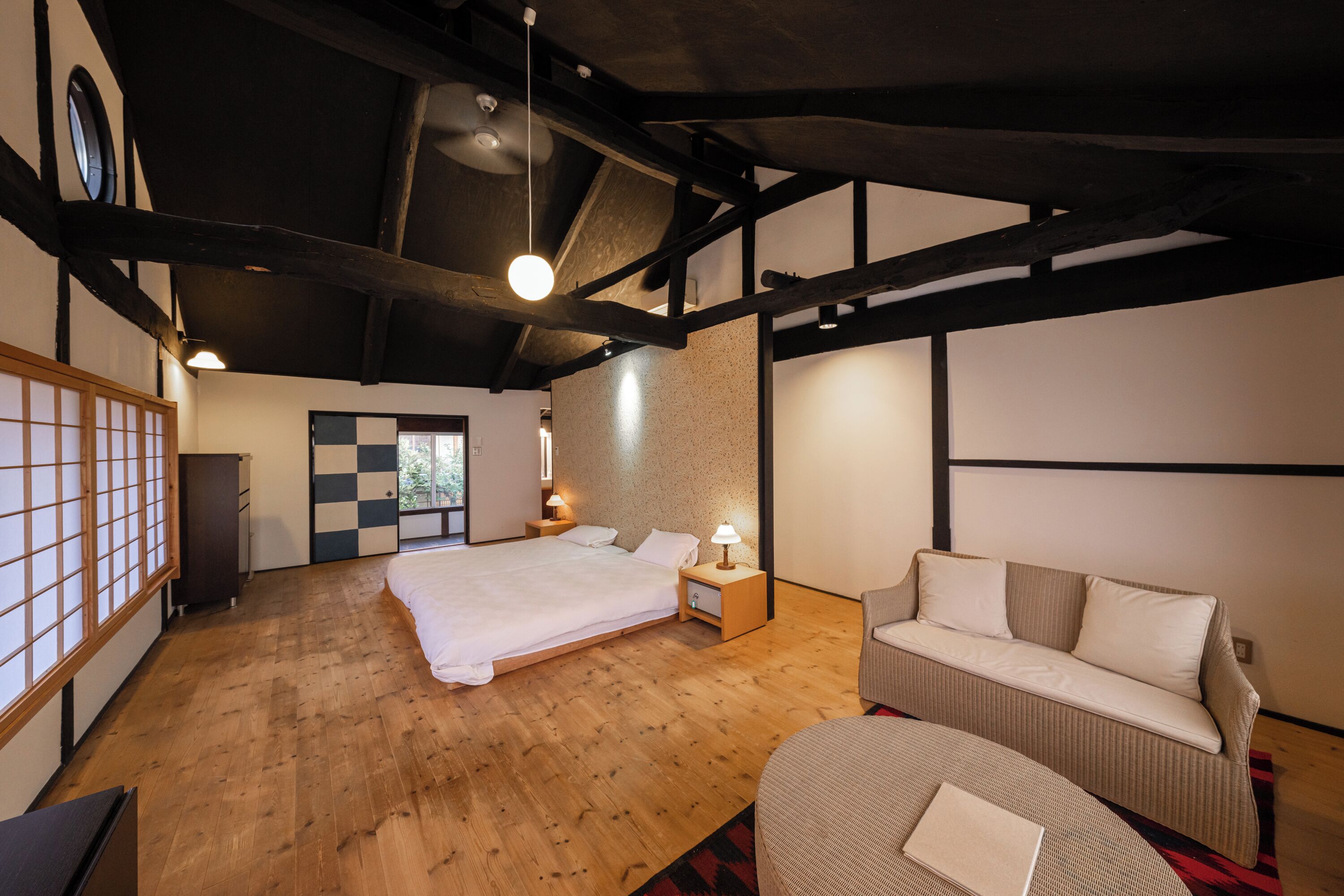 A bedroom with a large bed, a sofa, and a small table with a lamp.