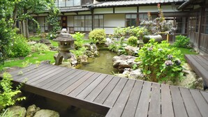 A traditional Japanese garden with a wooden bridge, koi pond, and various plants. - IZUTSURO (Tahara)