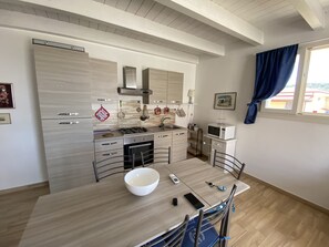 Ett modernt kök med en bänkskiva i trä, vitvaror i rostfritt stål och en matplats med bord och stolar.