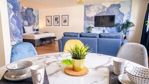 A modern living room with a sofa, a coffee table with a plant, and a TV mounted on the wall. - City Loft | 5 Min Rhein-Galerie (Ludwigshafen am Rhein)