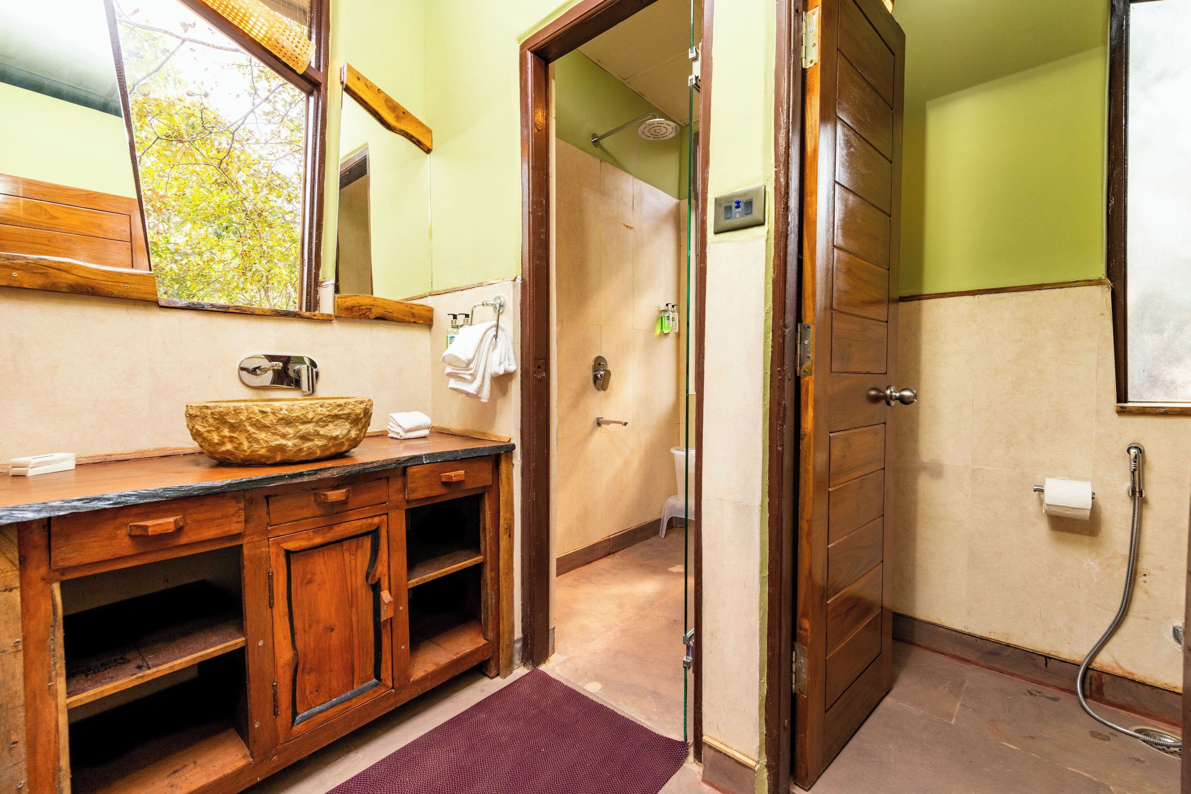 Une salle de bain avec un meuble-lavabo en bois, un grand miroir, un espace douche et un porte-rouleau de papier toilette visible.