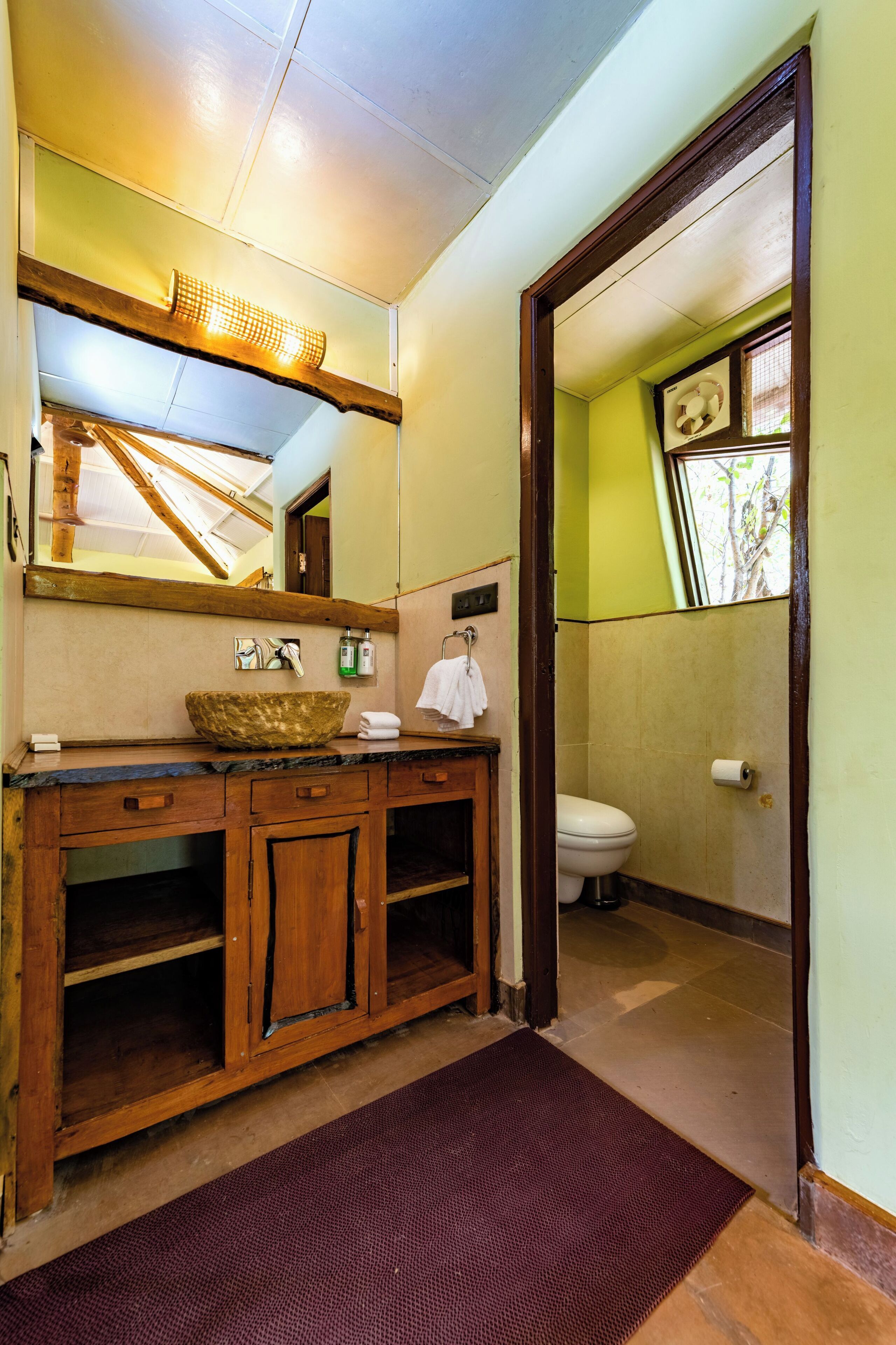 Une salle de bain avec un meuble-lavabo en bois, un grand miroir, un lavabo et des toilettes.