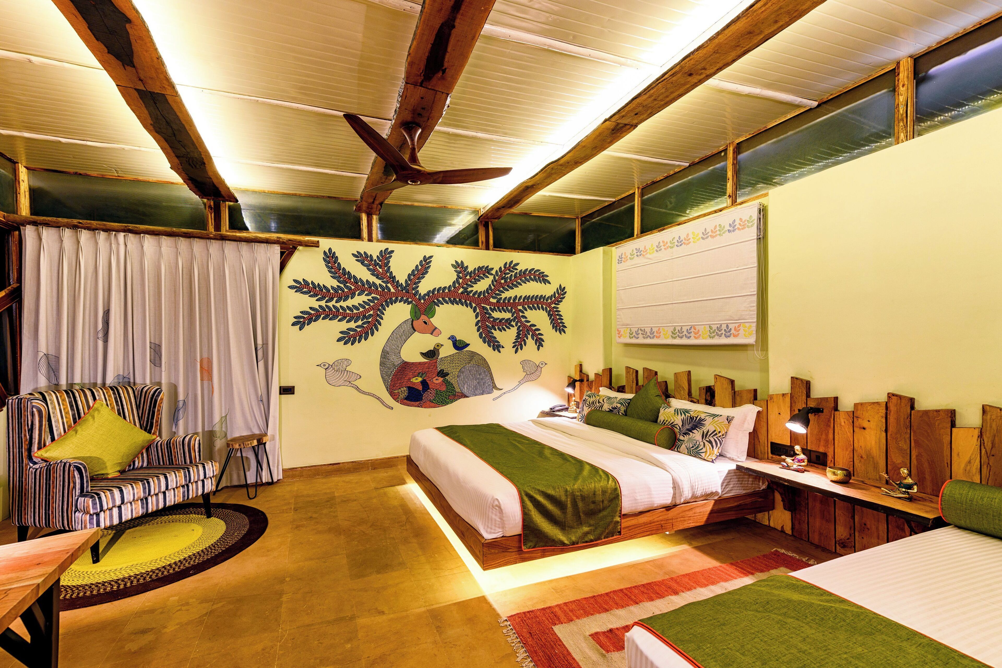 A cozy bedroom with a bed, a sofa, a small table, and a ceiling fan.