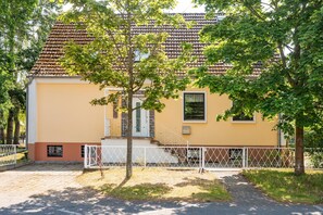 A two-story building with a tiled roof, a small balcony, and a fenced front yard. - Großzügige Ferienwohnung in Ahlbeck in Zentraler Lage für max 4 Personen (Seebad Ahlbeck)