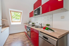 A compact kitchen with red cabinets, a built-in microwave, a sink, and a dishwasher. - Großzügige Ferienwohnung in Ahlbeck in Zentraler Lage für max 4 Personen (Seebad Ahlbeck)