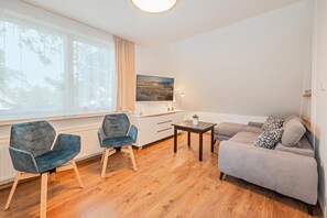 A modern living room with a sofa, two chairs, a coffee table, and a painting on the wall. - Großzügige Ferienwohnung in Ahlbeck in Zentraler Lage für max 4 Personen (Seebad Ahlbeck)