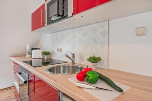 A modern kitchen with stainless steel appliances, a wooden countertop, and a red backsplash. - Großzügige Ferienwohnung in Ahlbeck in Zentraler Lage für max 4 Personen (Seebad Ahlbeck)