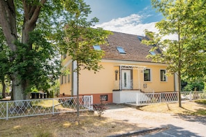 A two-story house with a tiled roof, a small porch, and a fenced yard.