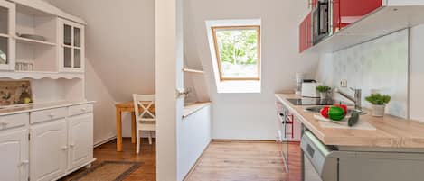 Une cuisine avec des meubles blancs, une table à manger en bois et une fenêtre.