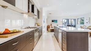 Una cocina moderna con electrodomésticos de acero inoxidable, una isla grande y un comedor con vistas.