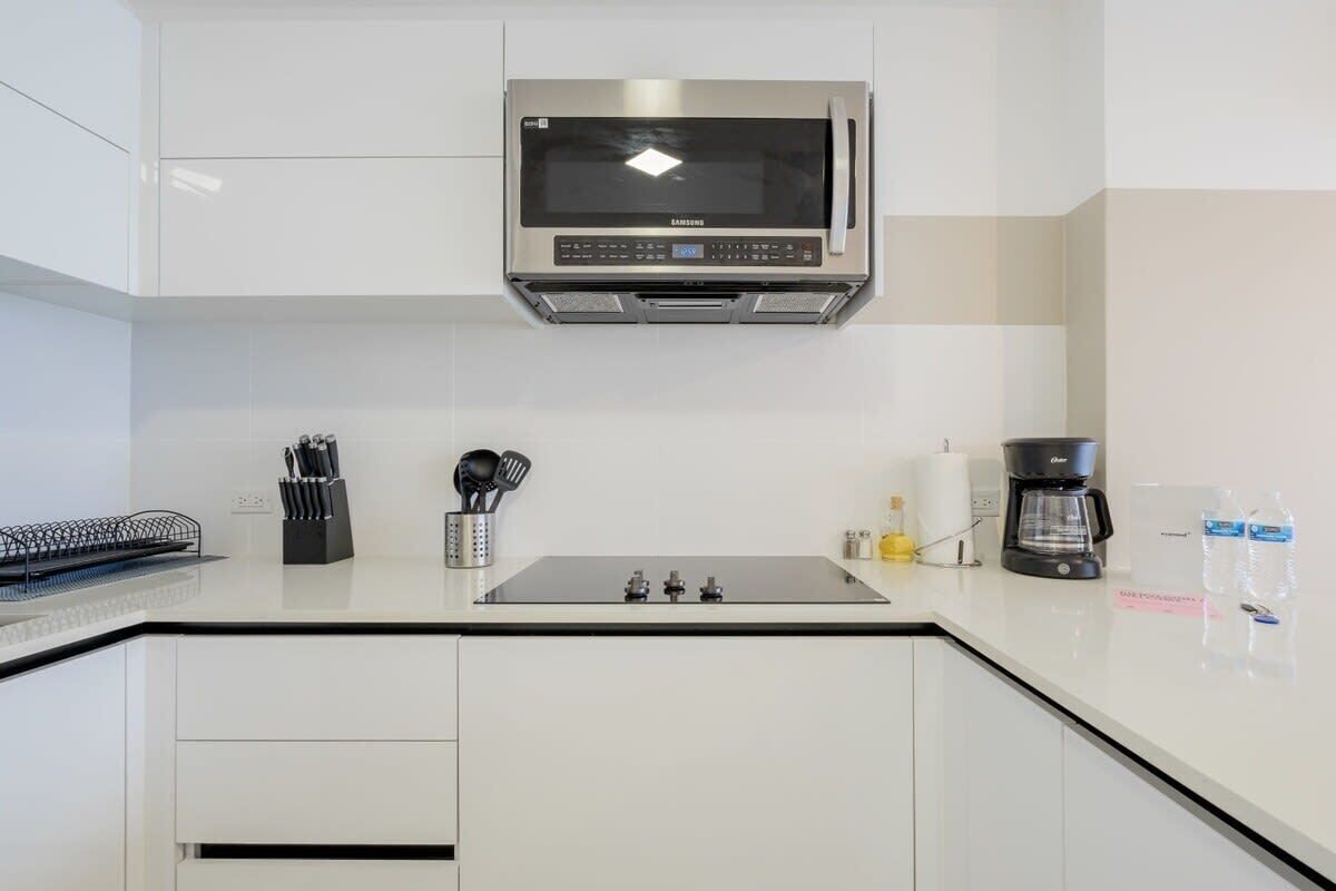Una cucina moderna con un forno a microonde integrato, una macchina per il caffè e diversi utensili sul piano di lavoro.