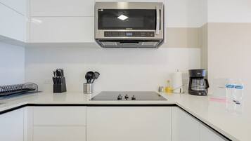 Una cucina moderna con un forno a microonde integrato, una macchina per il caffè e diversi utensili sul piano di lavoro.