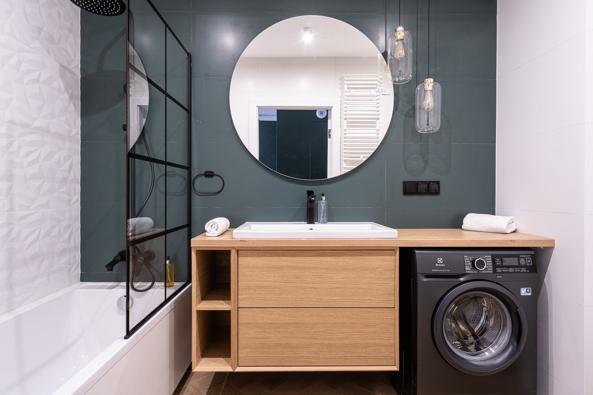 Un bagno moderno con lavatrice integrata, uno specchio grande e cabina doccia in vetro.