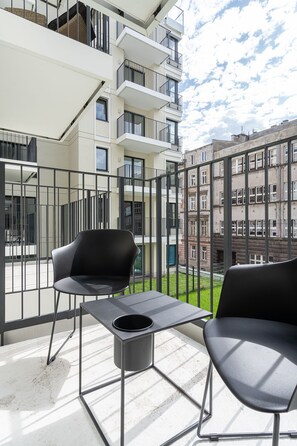 A balcony with two black chairs, a small table, and a metal railing. - RentPlanet - Przedmieście Oławskie (Wroclaw)