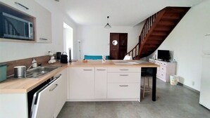 Moderni keittiö, jossa on puinen työtaso, valkoiset kaapit ja sisäänrakennettu astianpesukone.