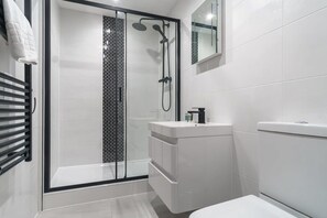 A modern bathroom with a glass-enclosed shower, a white sink, and a toilet. - Central Preston Contemporary 1 Bedroom Apartment (Preston)