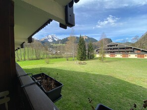 A view from a balcony overlooking a grassy field with a building and mountains in the background. - Quiet studio near Abondance center, south-facing balcony, ski locker, parking (Abondance)