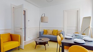 Un salon moderne avec un canapé, une table basse ronde et une table à manger pour quatre personnes.