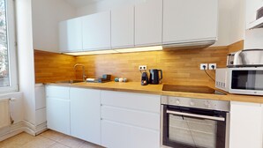 Une cuisine moderne avec des meubles blancs, un plan de travail en bois, un four encastré et un four à micro-ondes.