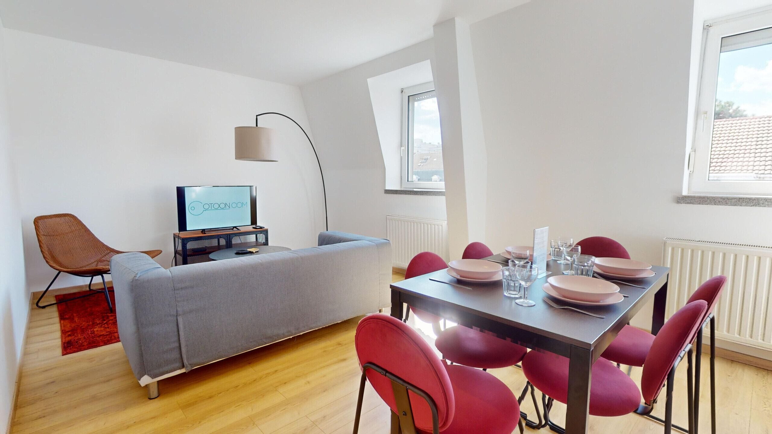 Een moderne woonkamer met een bank, een televisie, een eettafel met stoelen en een raam met uitzicht.