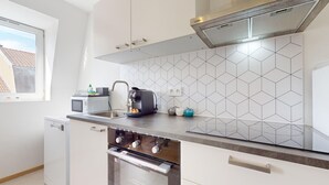 A modern kitchen with white cabinets, a stainless steel sink, a built-in oven, and a coffee maker.