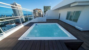 A rooftop with a hot tub, wooden deck, and a view of surrounding buildings. - Majestic & Spacious1b Downton Gym Pool (Santo Domingo)