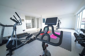 A gym with stationary bikes, treadmills, and dumbbells.