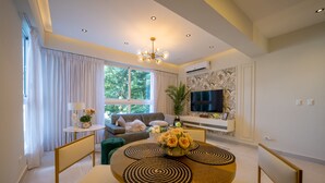 A modern living room with a sofa, TV, and a dining area with a round table and chairs. - Majestic & Spacious1b Downton Gym Pool (Santo Domingo)