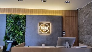 Un espace d’accueil d’hôtel au design moderne, comprenant un comptoir de réception portant l’inscription « RÉCEPTION » et une enseigne indiquant « HÔTEL KALFA ».