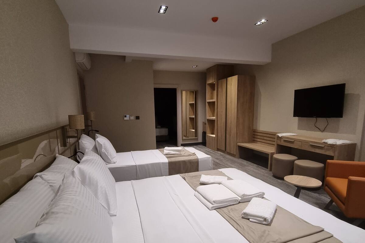 Habitación de hotel con una cama grande, un escritorio, una silla, un televisor y un espejo.