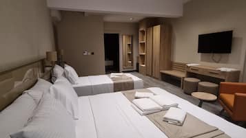 A hotel room with a large bed, a desk, a chair, a TV, and a mirror.