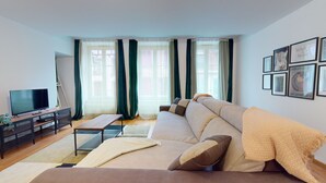 Ein modernes Wohnzimmer mit einer Couch, einem Fernseher und einem Schreibtisch mit einem Computer.