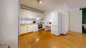 Eine moderne Küche mit weißen Schränken, einer Holzarbeitsplatte, einem eingebauten Backofen und einem weißen Kühlschrank.