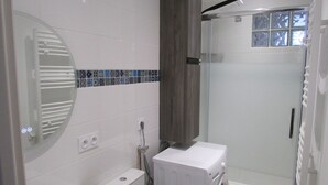 A modern bathroom with a white sink, a mirror, and a shower area. - Appartement Neuf Bages Avec Balcon (Bages)