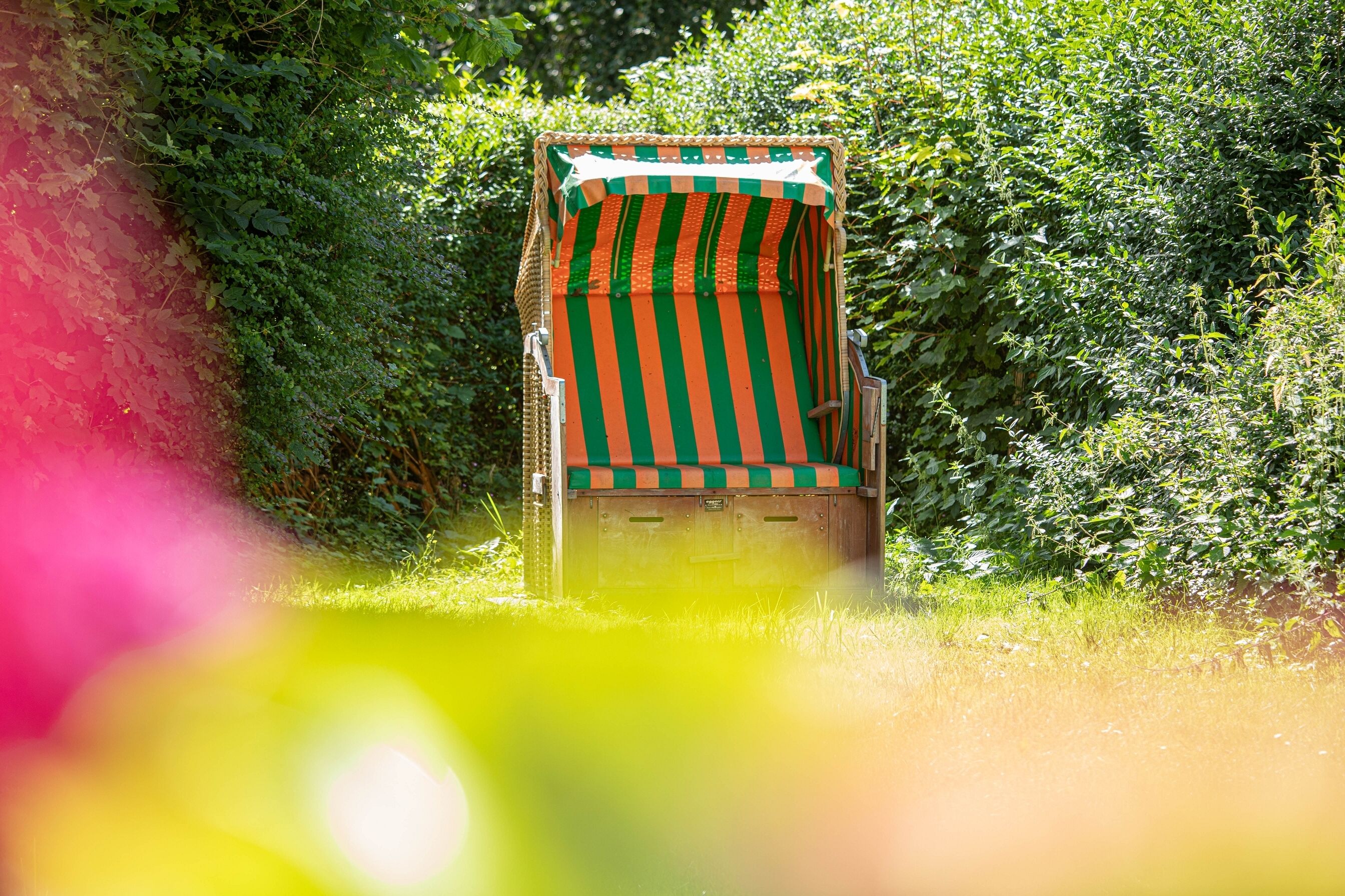 A striped beach chair in a lush green garden.