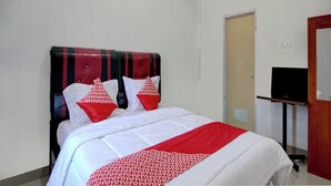 Quarto de hotel com uma cama, uma televisão em suporte e uma porta.