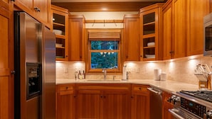 A kitchen with wooden cabinets, a stainless steel refrigerator, a sink, and a stove. - Your Michigan Cottage Awaits! (Douglas)