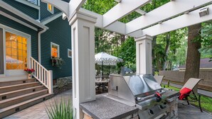 An outdoor patio with a grill, stone steps, and a covered seating area. - Your Michigan Cottage Awaits! (Douglas)