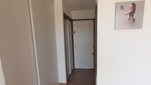 A hallway with a door at the end, a tiled floor, and a framed picture on the wall. - Airy Studio with AC, Terrace, and Garage - Centrally Located in Agde (Cap d'Agde naturisme)