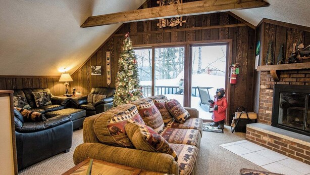 Ein gemütliches Wohnzimmer mit Kamin, Ledersofas und einem Weihnachtsbaum.