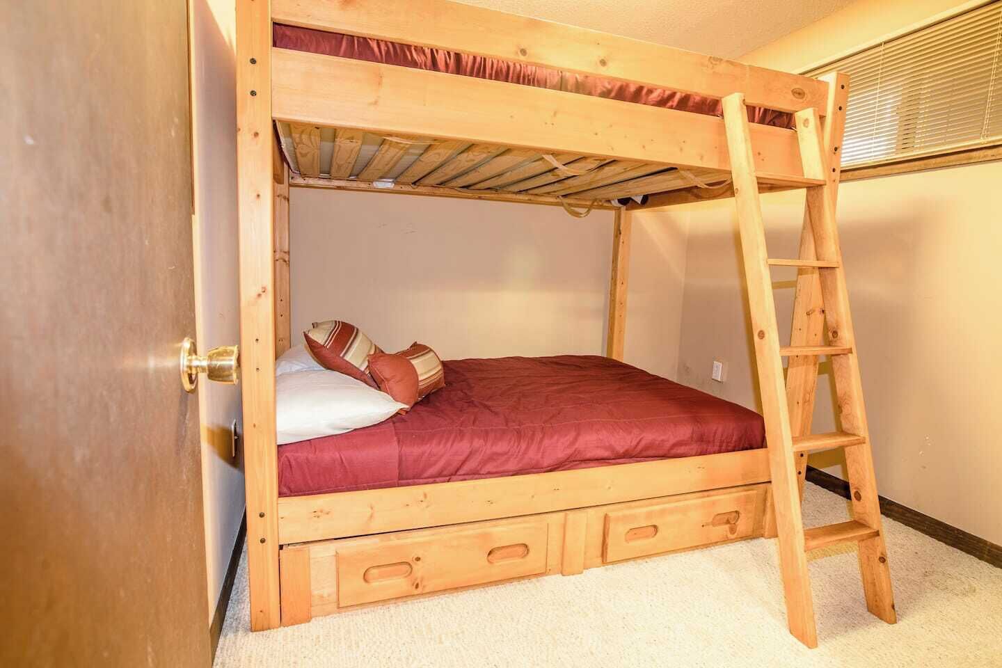Un letto a castello con una scala, una porta in legno e un pavimento rivestito di moquette.