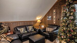 Ein gemütliches Wohnzimmer mit einem ledernen Ecksofa, einem kleinen Beistelltisch und einem Weihnachtsbaum.